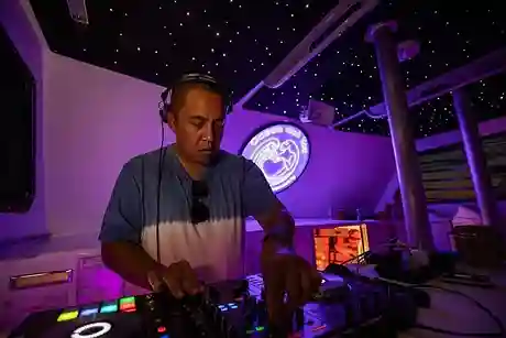The dj is seen in action, surrounded by mixing equipment and vibrant lights, creating an energetic and rhythmic atmosphere
